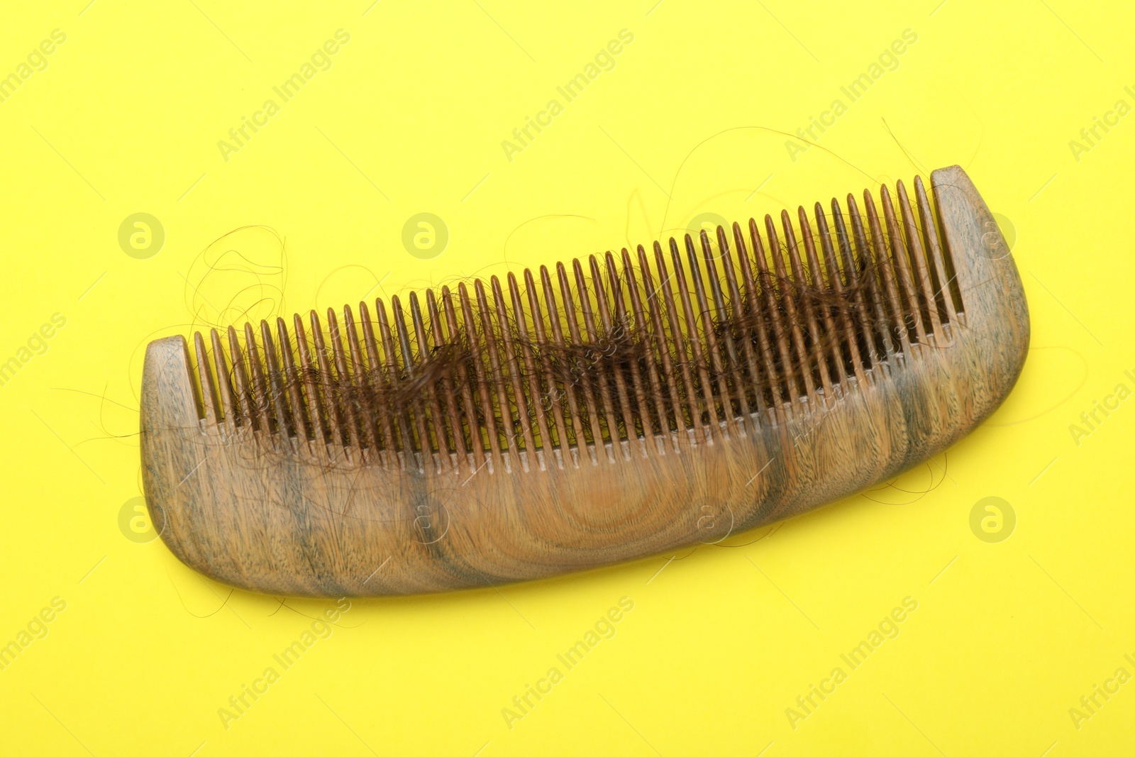 Photo of One comb with lost hair on yellow background, top view. Alopecia problem