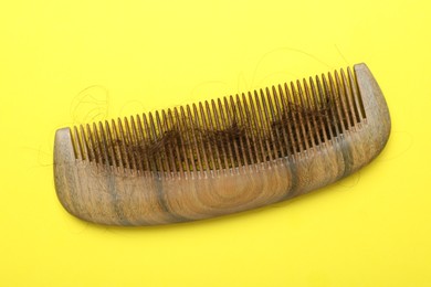 Photo of One comb with lost hair on yellow background, top view. Alopecia problem