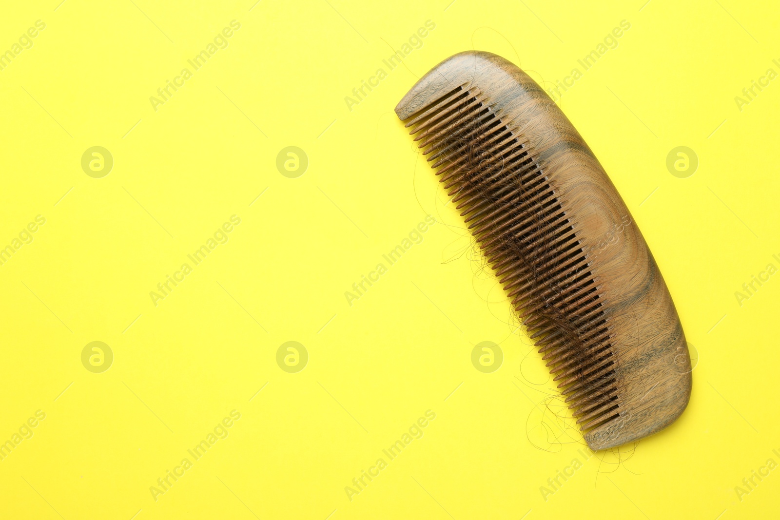 Photo of One comb with lost hair on yellow background, top view. Space for text