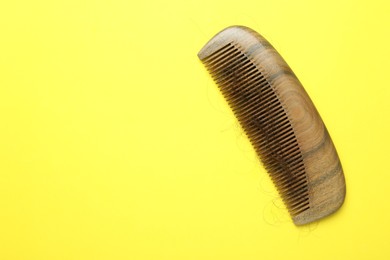 One comb with lost hair on yellow background, top view. Space for text