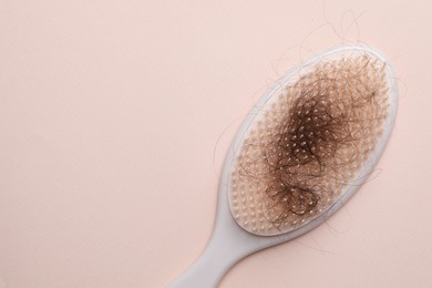 One brush with lost hair on light pink background, top view. Space for text