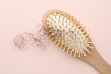 Photo of One brush with lost hair on light pink background, top view