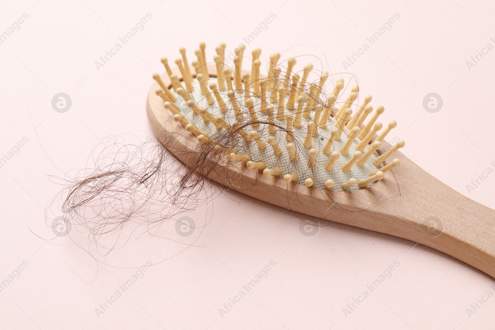 Photo of One brush with lost hair on light pink background. Alopecia problem