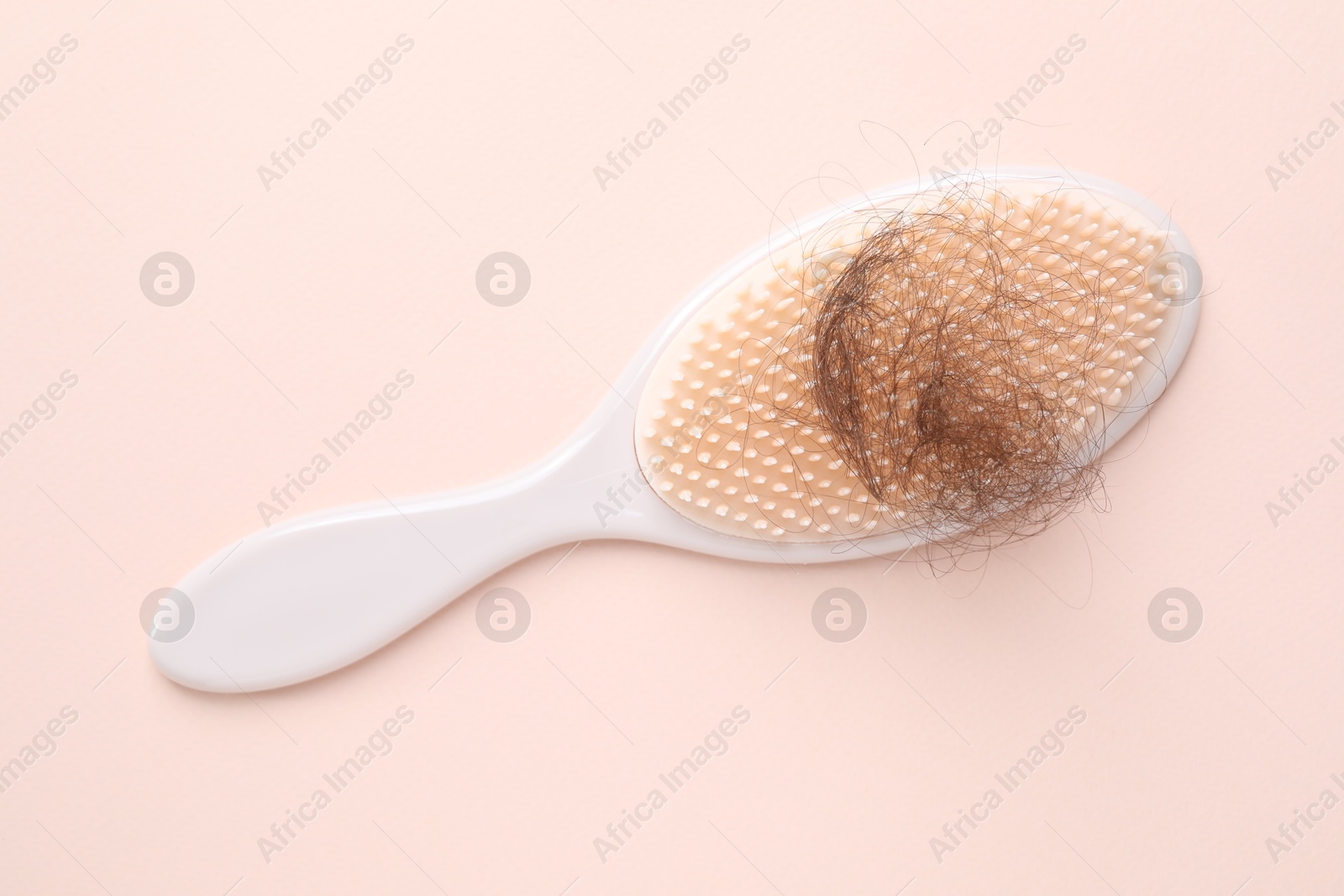 Photo of One brush with lost hair on light pink background, top view