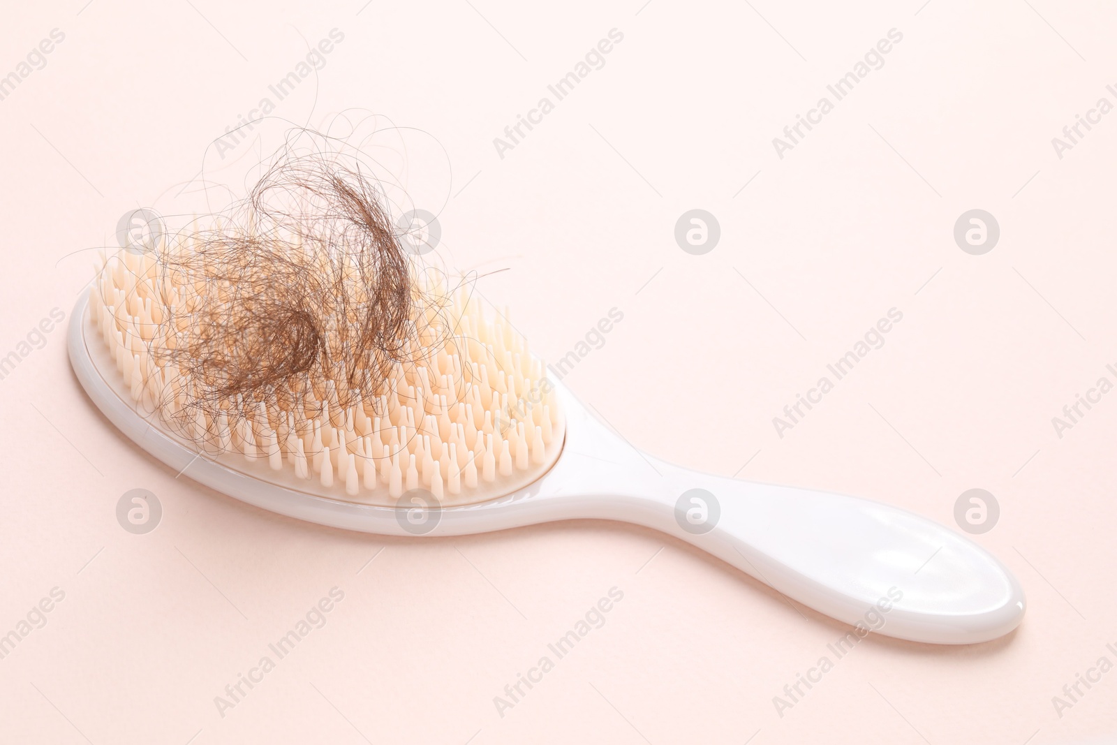 Photo of One brush with lost hair on light pink background. Alopecia problem