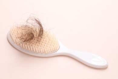 Photo of One brush with lost hair on light pink background. Alopecia problem