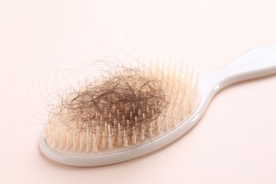 Photo of One brush with lost hair on light pink background, closeup. Alopecia problem