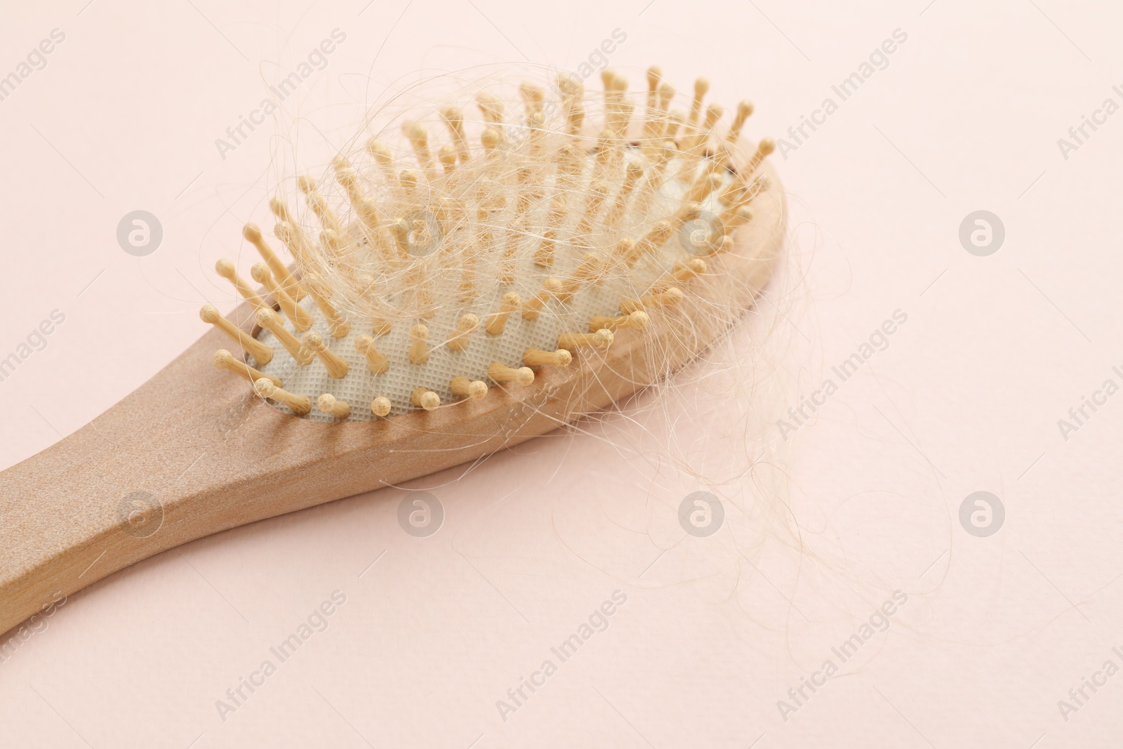 Photo of One brush with lost hair on light pink background. Alopecia problem