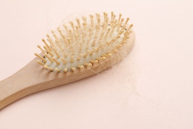 Photo of One brush with lost hair on light pink background. Alopecia problem