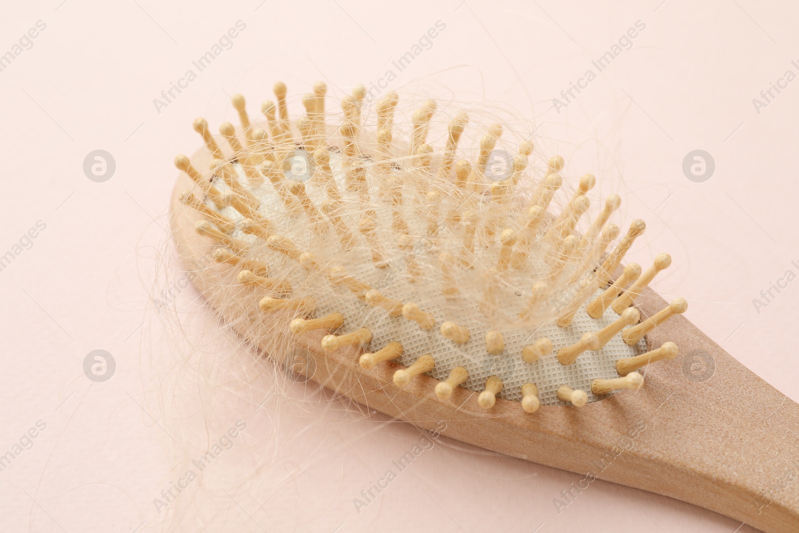 Photo of One brush with lost hair on light pink background. Alopecia problem