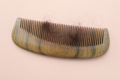 Photo of Comb with lost hair on light pink background, top view