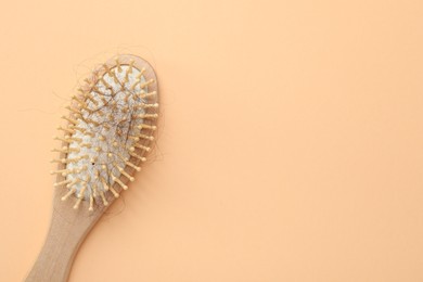 Photo of One brush with lost hair on beige background, top view. Space for text