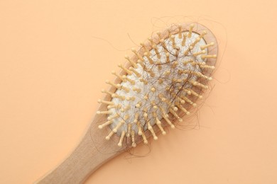 Photo of One brush with lost hair on beige background, top view