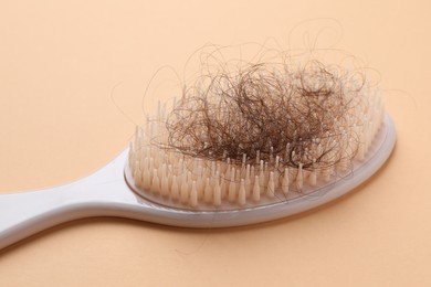 One brush with lost hair on beige background, closeup. Alopecia problem