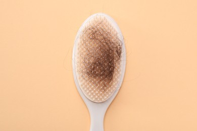 Photo of One brush with lost hair on beige background, top view