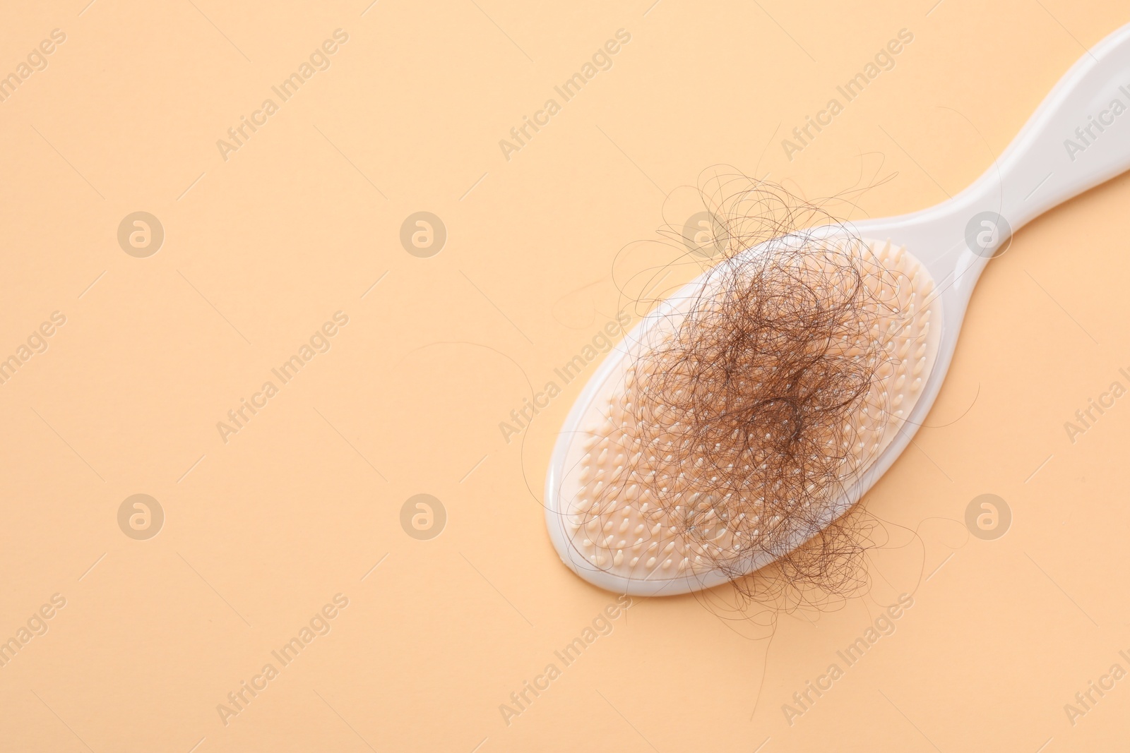 Photo of One brush with lost hair on beige background, top view. Space for text