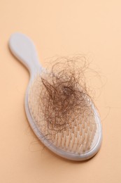 One brush with lost hair on beige background, closeup. Alopecia problem