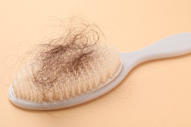 One brush with lost hair on beige background, closeup. Alopecia problem