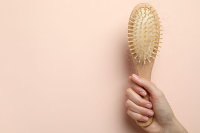 Woman with brush and lost hair on light pink background, top view. Space for text