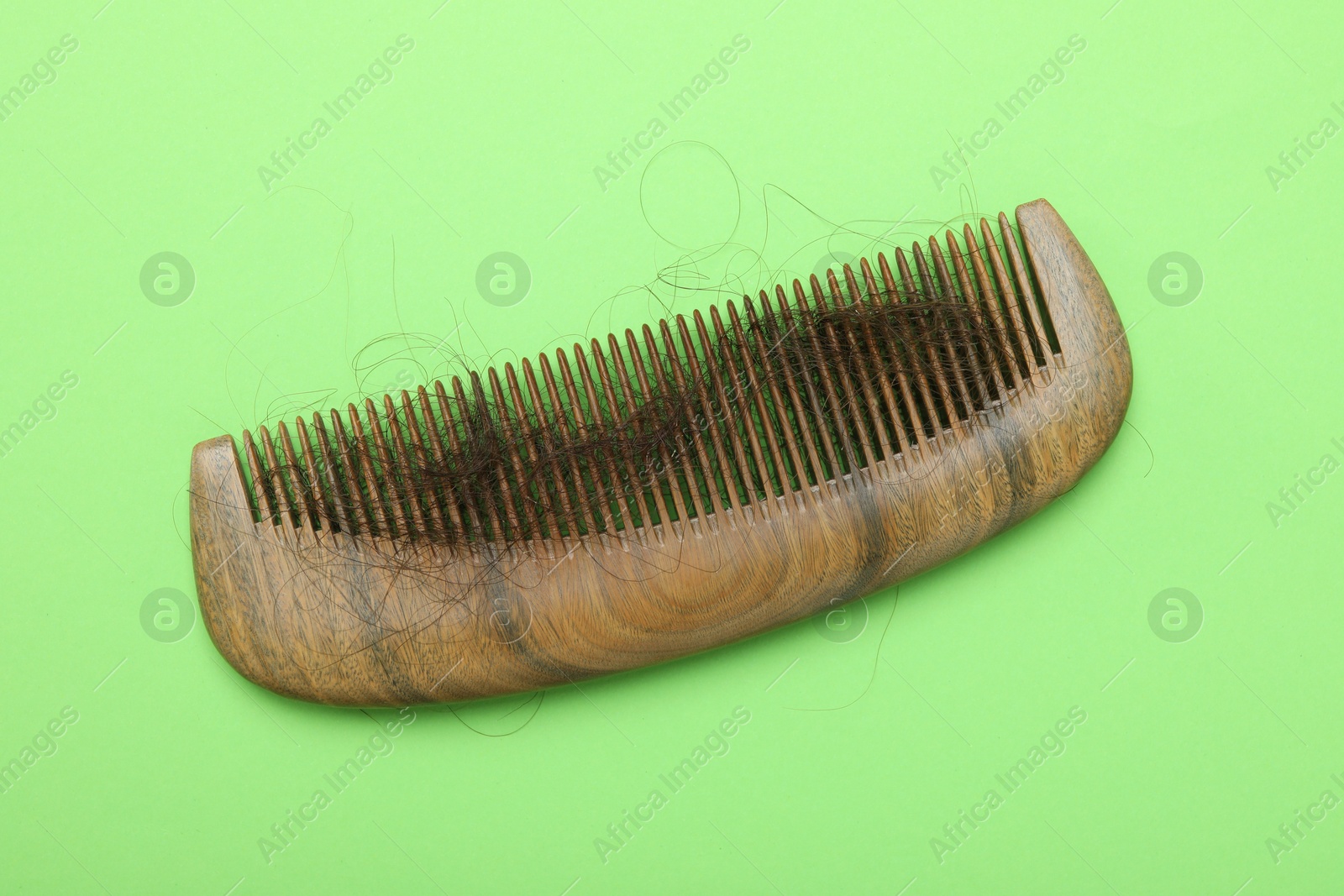 Photo of One comb with lost hair on light green background, top view