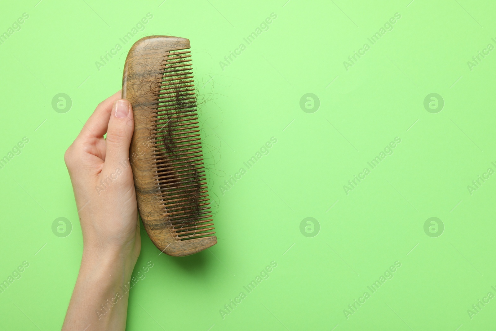 Photo of Woman with comb and lost hair on light green background, top view. Space for text