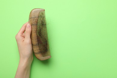 Photo of Woman with comb and lost hair on light green background, top view. Space for text