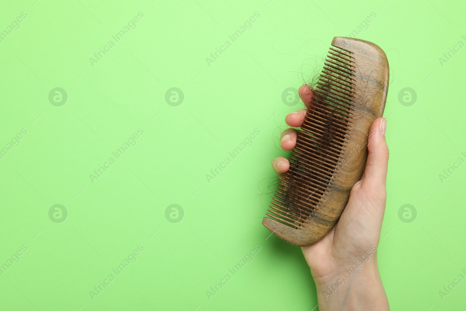 Photo of Woman with comb and lost hair on light green background, top view. Space for text