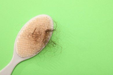 Photo of One brush with lost hair on light green background, top view. Space for text