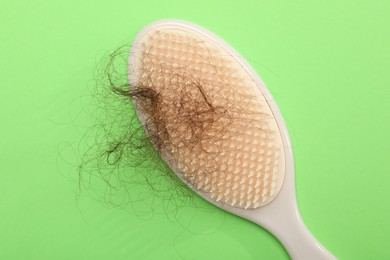 One brush with lost hair on light green background, top view