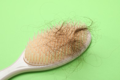 Photo of One brush with lost hair on light green background, closeup. Alopecia problem