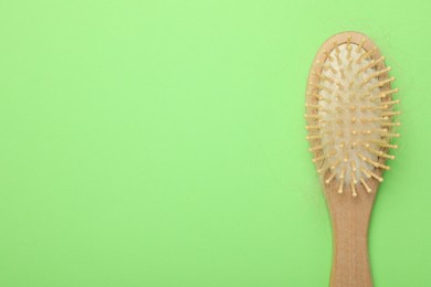 One brush with lost hair on light green background, top view. Space for text