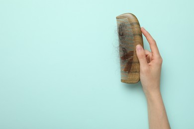 Woman with comb and lost hair on light blue background, top view. Space for text