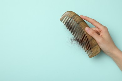 Photo of Woman with comb and lost hair on light blue background, top view. Space for text