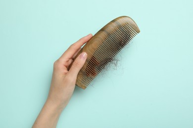 Woman with comb and lost hair on light blue background, top view. Alopecia problem