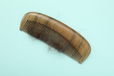 One comb with lost hair on light blue background, top view. Alopecia problem