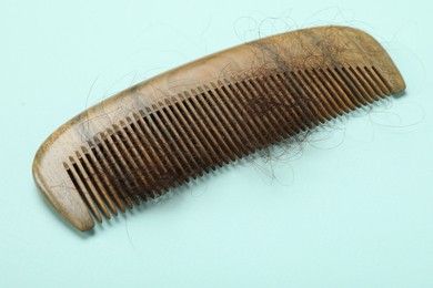 Photo of One comb with lost hair on light blue background. Alopecia problem