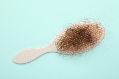 One brush with lost hair on light blue background, top view. Alopecia problem