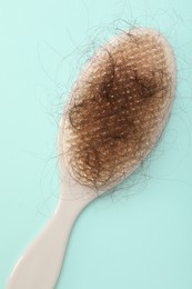 Photo of One brush with lost hair on light blue background, top view. Alopecia problem