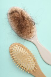 Photo of Brushes with lost hair on light blue background, flat lay. Alopecia problem