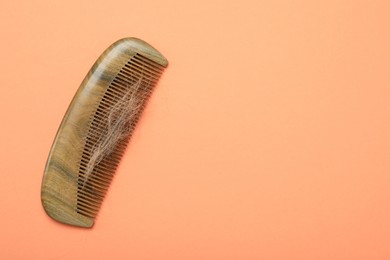 Photo of Comb with lost hair on coral background, top view. Space for text