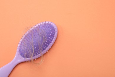 Photo of One brush with lost hair on coral background, top view. Space for text