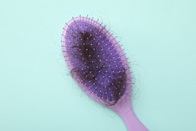 One brush with lost hair on light blue background, top view. Alopecia problem