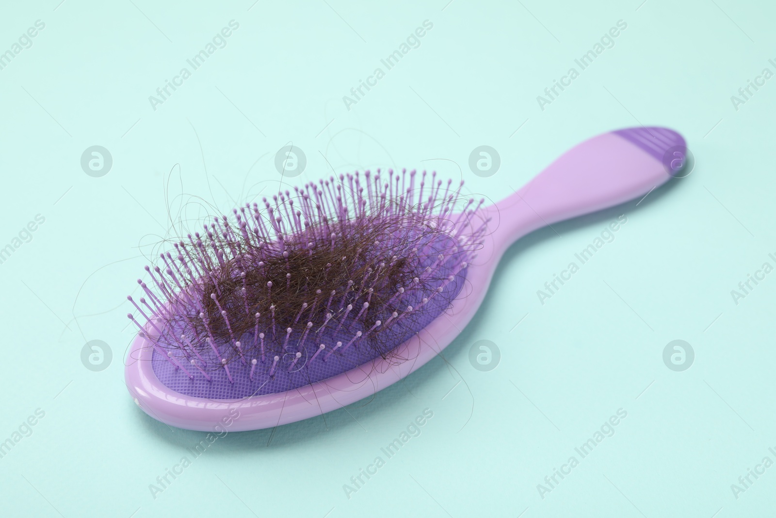 Photo of One brush with lost hair on light blue background. Alopecia problem