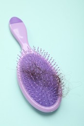 Photo of One brush with lost hair on light blue background. Alopecia problem