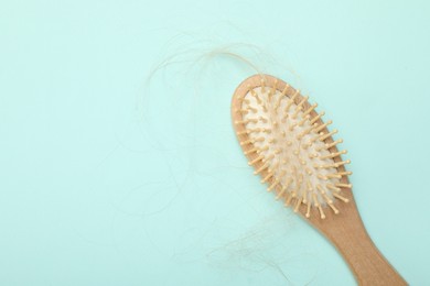 Photo of One brush with lost hair on light blue background, top view. Space for text