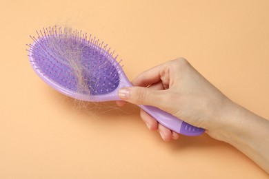 Photo of Woman with brush and lost hair on coral background, closeup. Alopecia problem