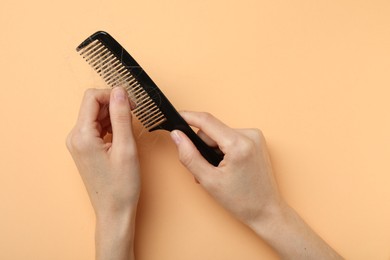 Woman taking her lost hair from comb on coral background, top view. Alopecia problem