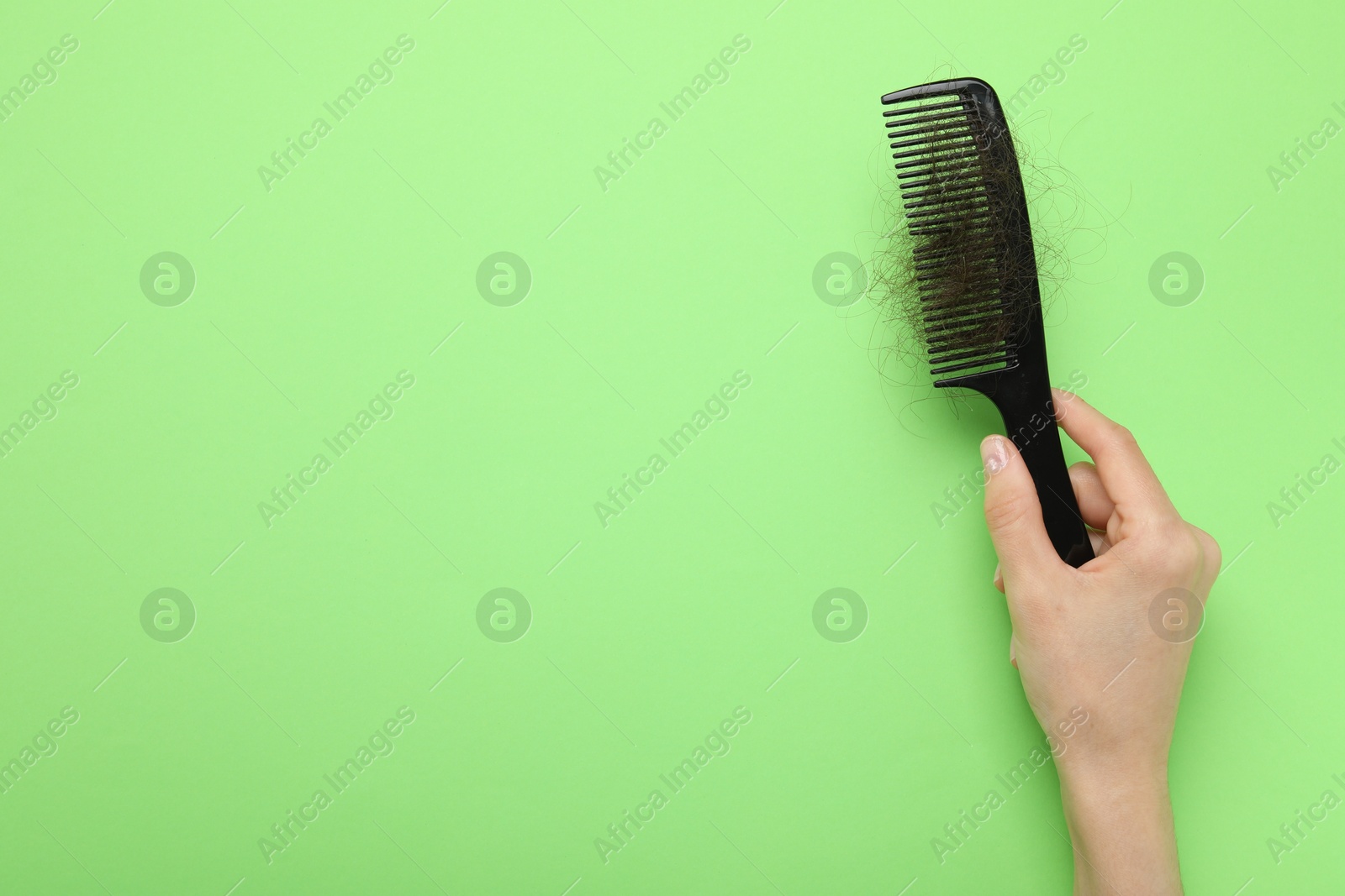 Photo of Woman with comb and lost hair on light green background, top view. Space for text