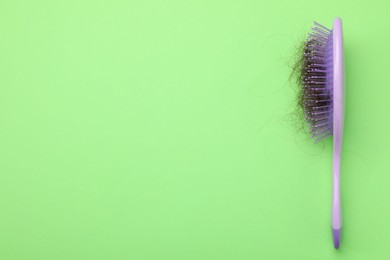 Photo of One brush with lost hair on light green background, top view. Space for text