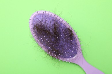 One brush with lost hair on light green background, top view. Alopecia problem